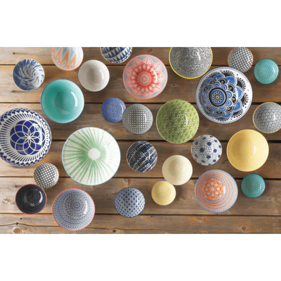 An assortment of colorful, patterned ceramic bowls arranged artistically on a wooden surface. The bowls feature various intricate designs and come in different sizes and vibrant colors.